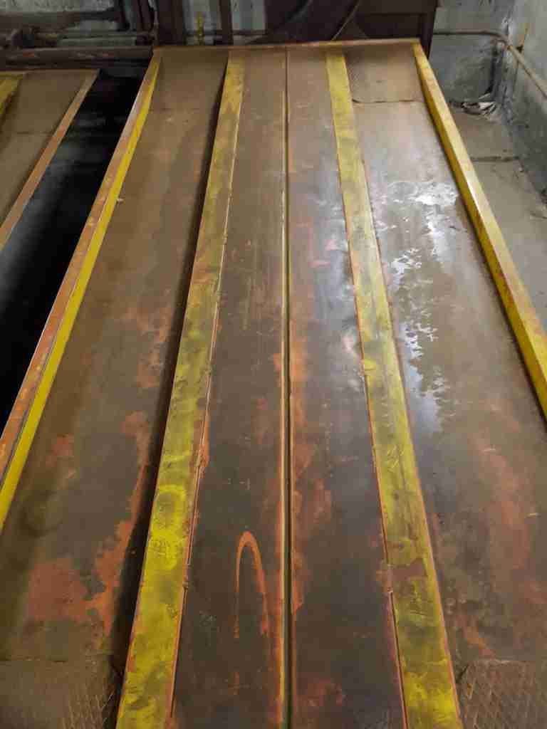 Interior del aparcamiento automático antes de la renovación - plataformas amarillas y rojas oxidadas, paredes sucias, iluminación deficiente